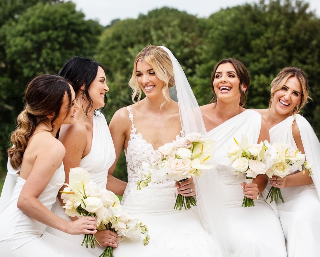 Bride laughing with bridesmaids and white bouquets